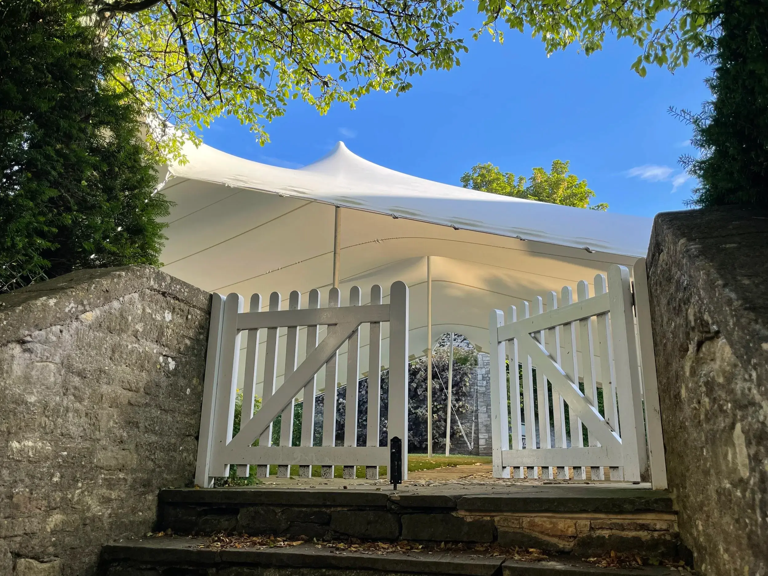 White stretch tent behind the garden gate at Cornwell Manor, Oxfordshire