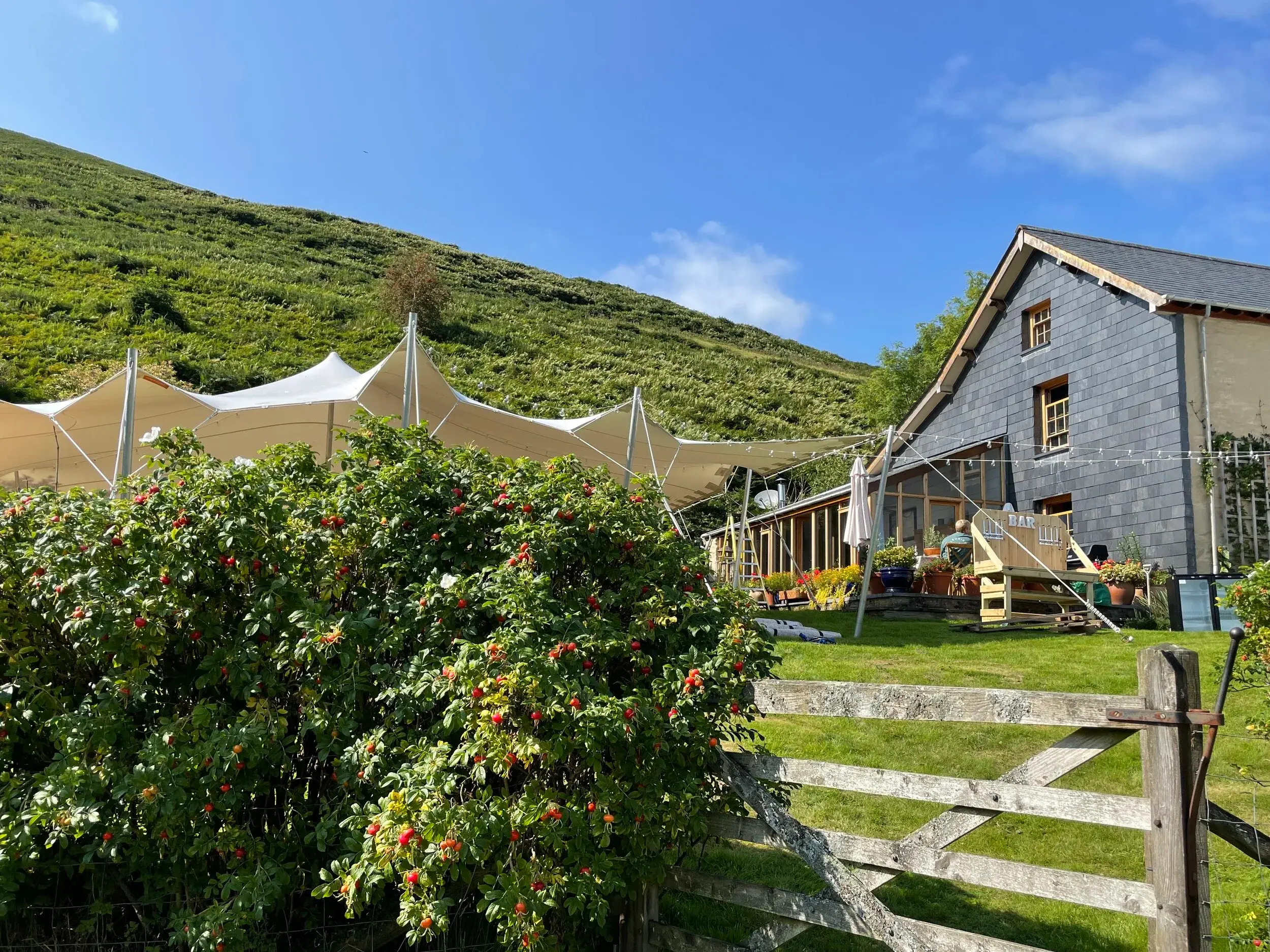 Stretch tent in a hillside garden beside a stone cottage